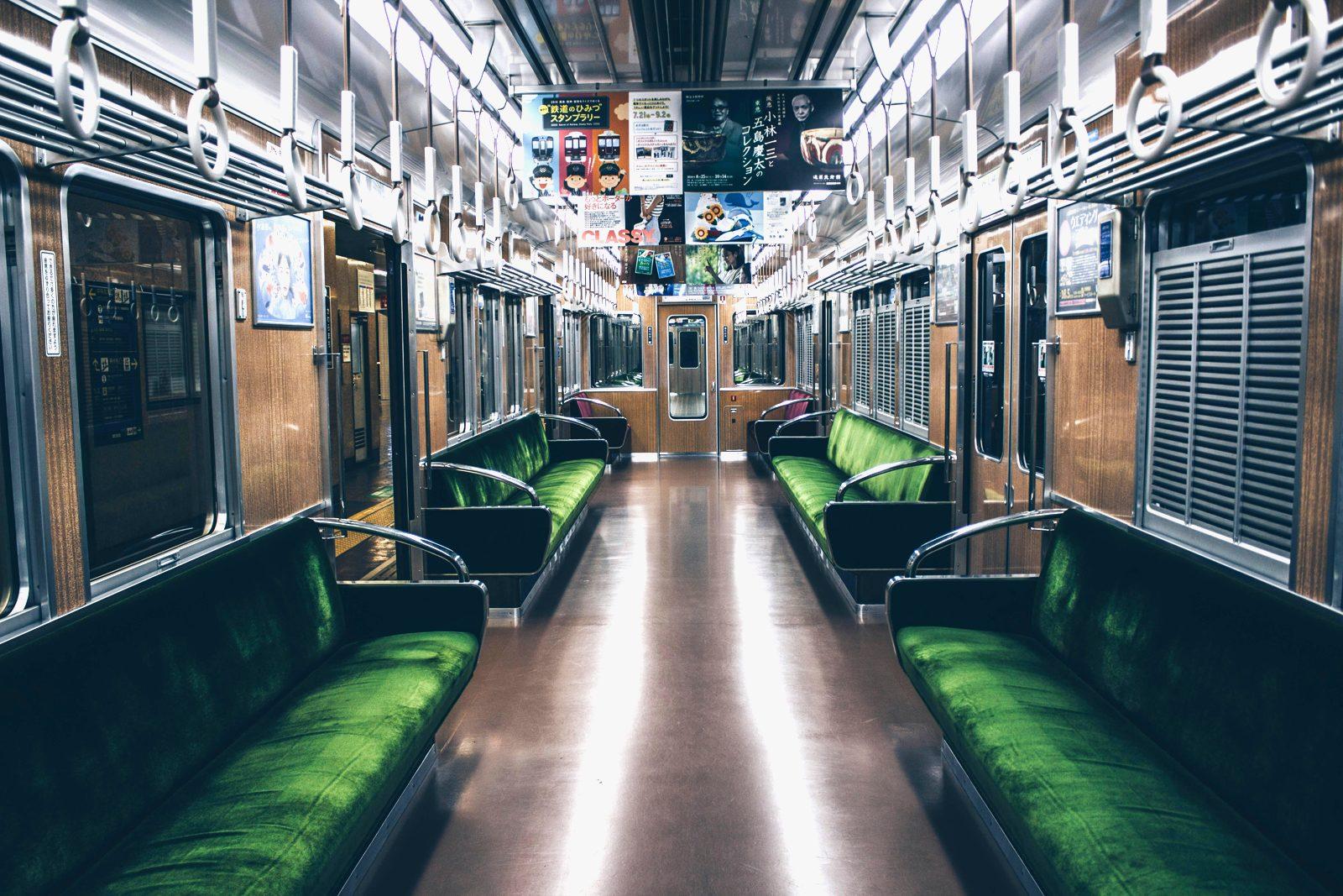 緑のシートと吊り革が並ぶ、誰も乗っていない阪急電車の車内