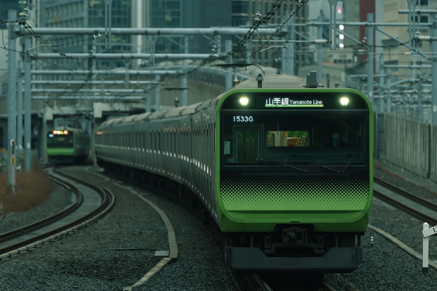 ビルの間のカーブを走ってくる山手線の緑の電車