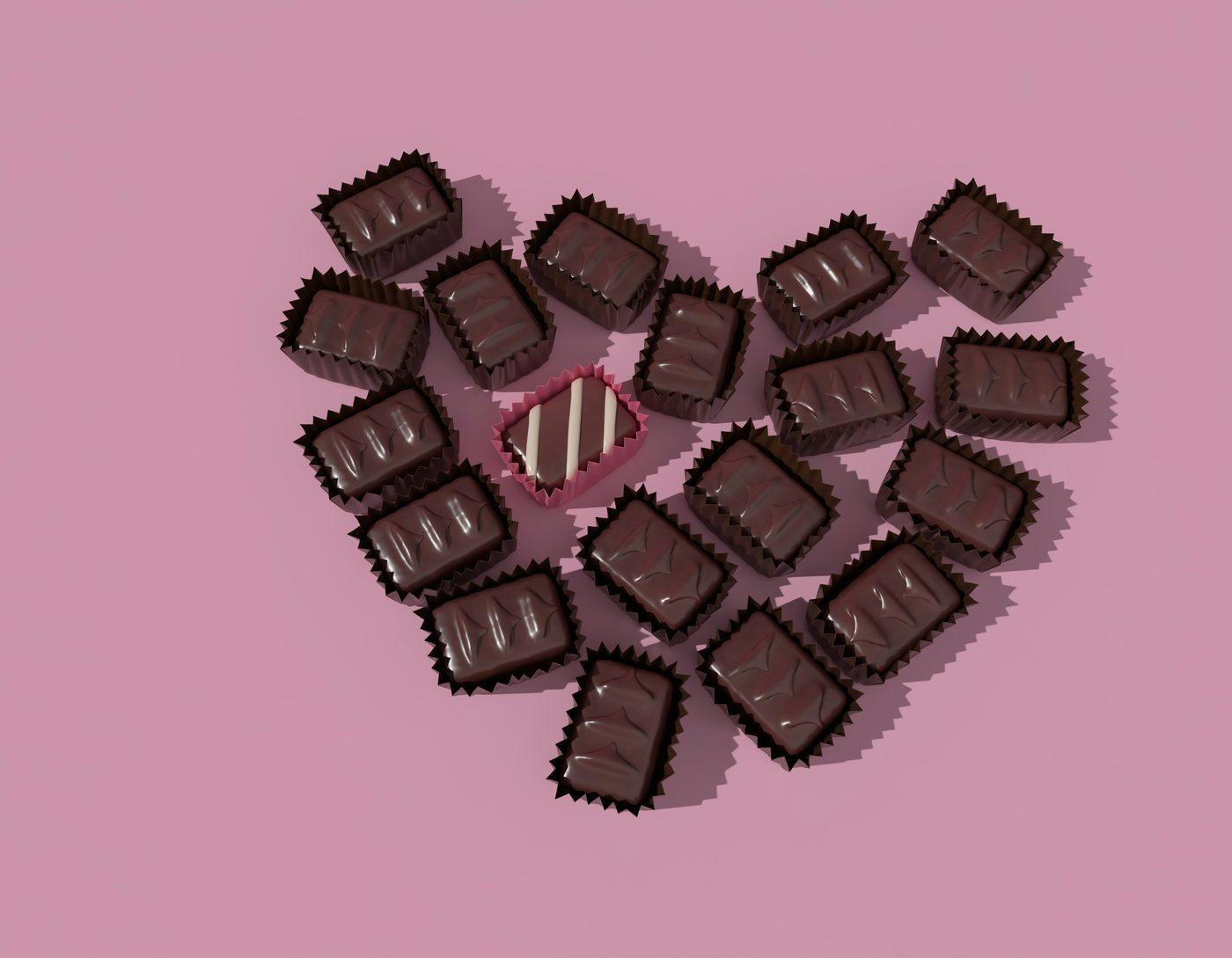 ピンクの背景に、ハートの形に並べられたひと粒チョコレート