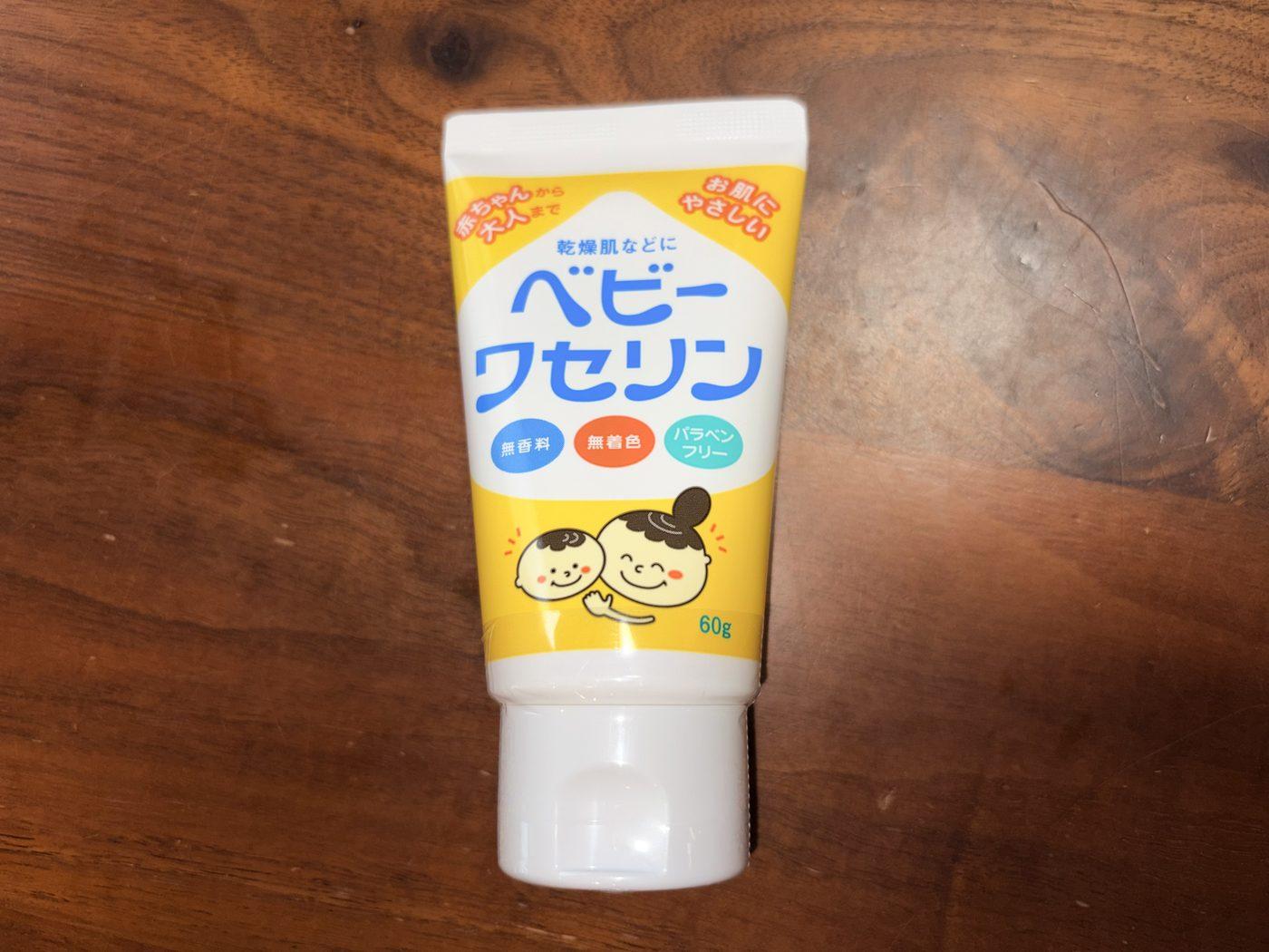 木のテーブルに置かれた、健栄製薬のベビーワセリン60gのチューブ