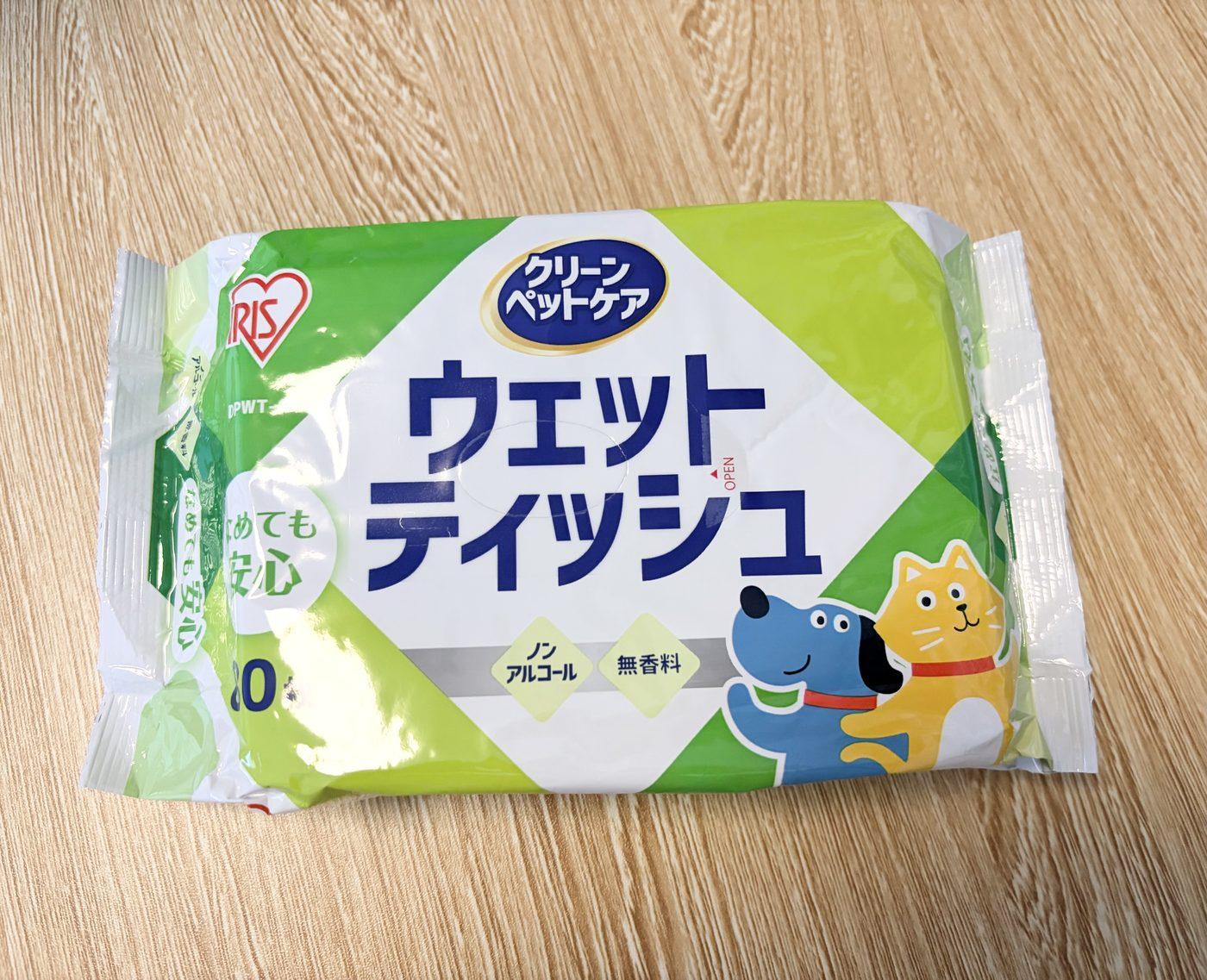 木目のテーブルに置かれた、アイリスオーヤマ「クリーンペットケア ウェットティッシュ」のパッケージ。ノンアルコール・無香料の表記